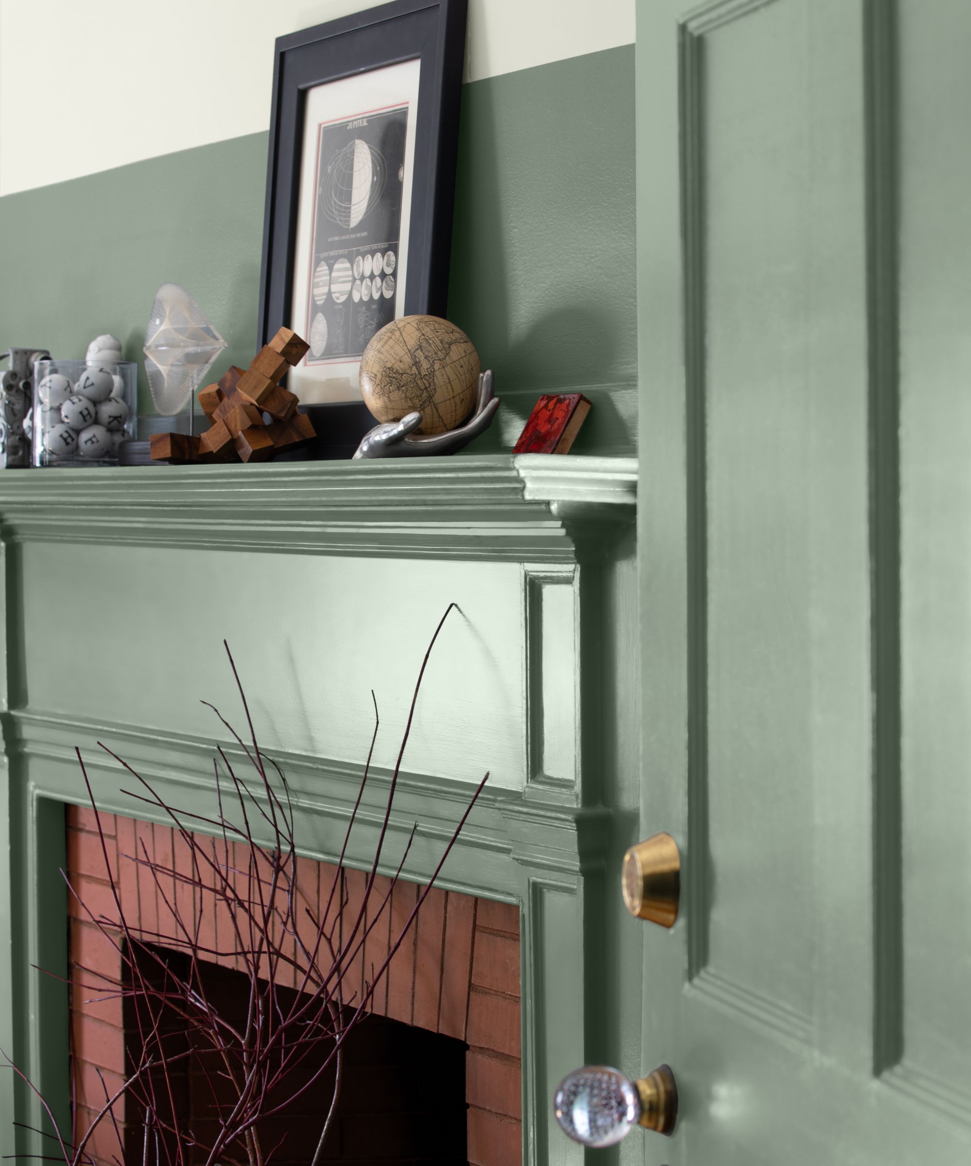 Close up of the fireplace painted in the middle of green, decor on the black frame with picture, the door painted the same green
