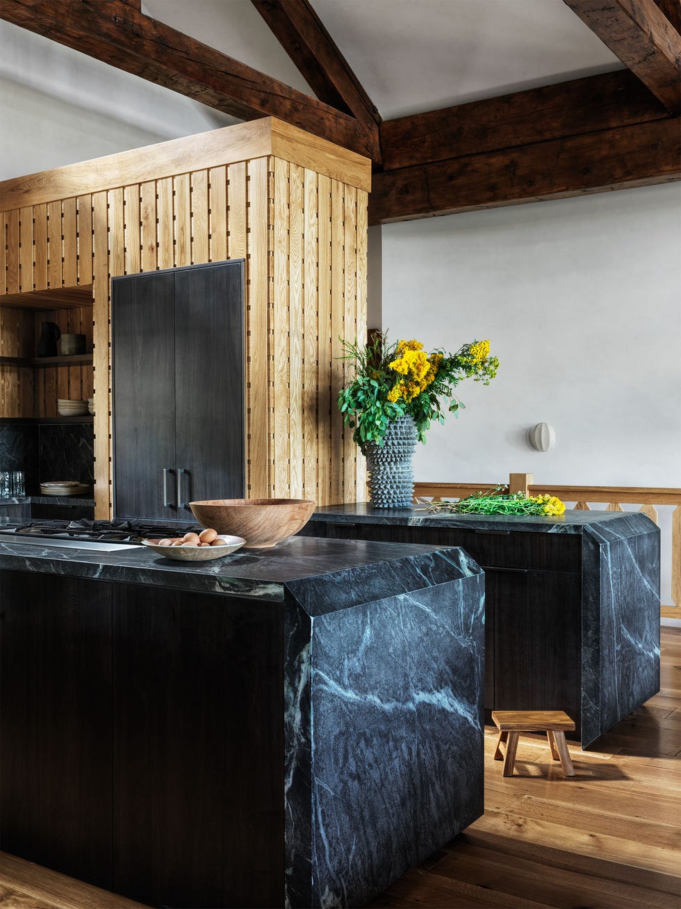 Electrician - Elle Decor Two dark marble islands with light floor and a rear sanding wall with the shelves and cabinets as well as a plant wood floor in nature