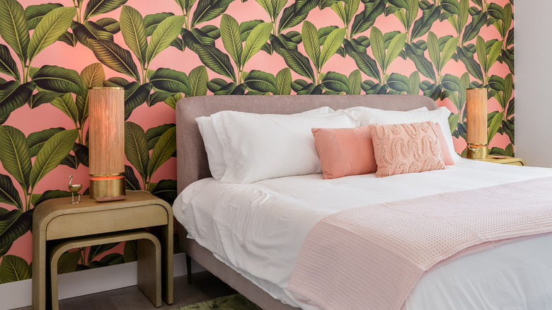 Bedroom with tropically patterned pink accent wall behind the bed
