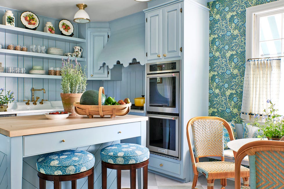 A kitchen with blue cupboards and pattern wallpaper