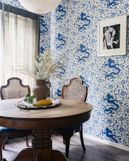 Dining area with a round wooden table with a vase made of dried flowers, fruit on a silver tray and blue dragon harness.