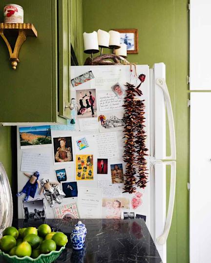 Refrigerator with notes, photos and dried peppers next to a lime peel on a dark worktop.