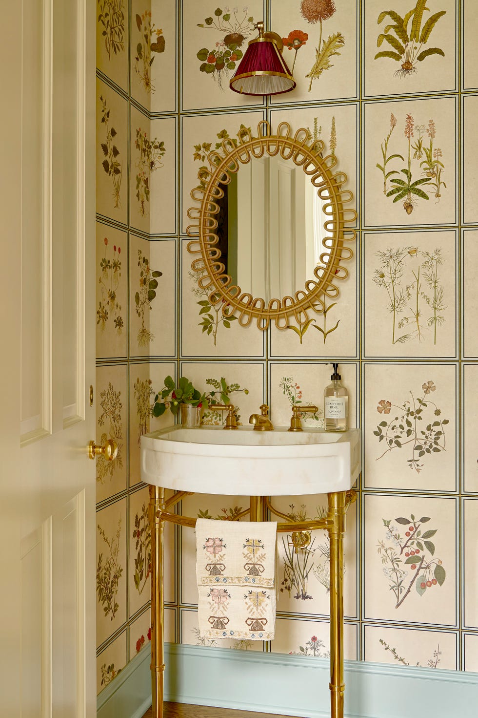 Powder bath with botanical wallpaper and slim washbasin and metallic mirror