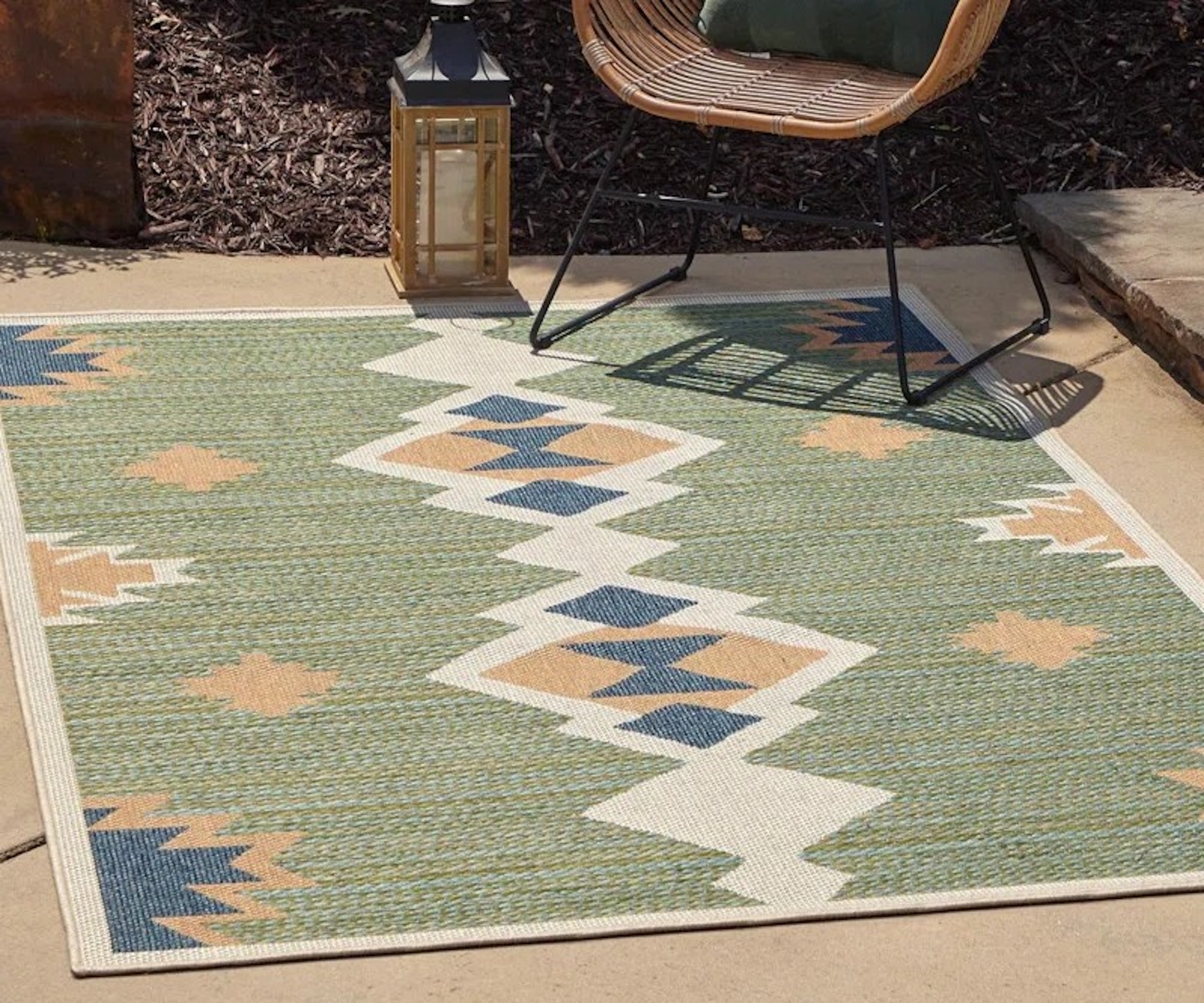 Morrocan inspired carpet with green and blue coloring, with a terrace chair
