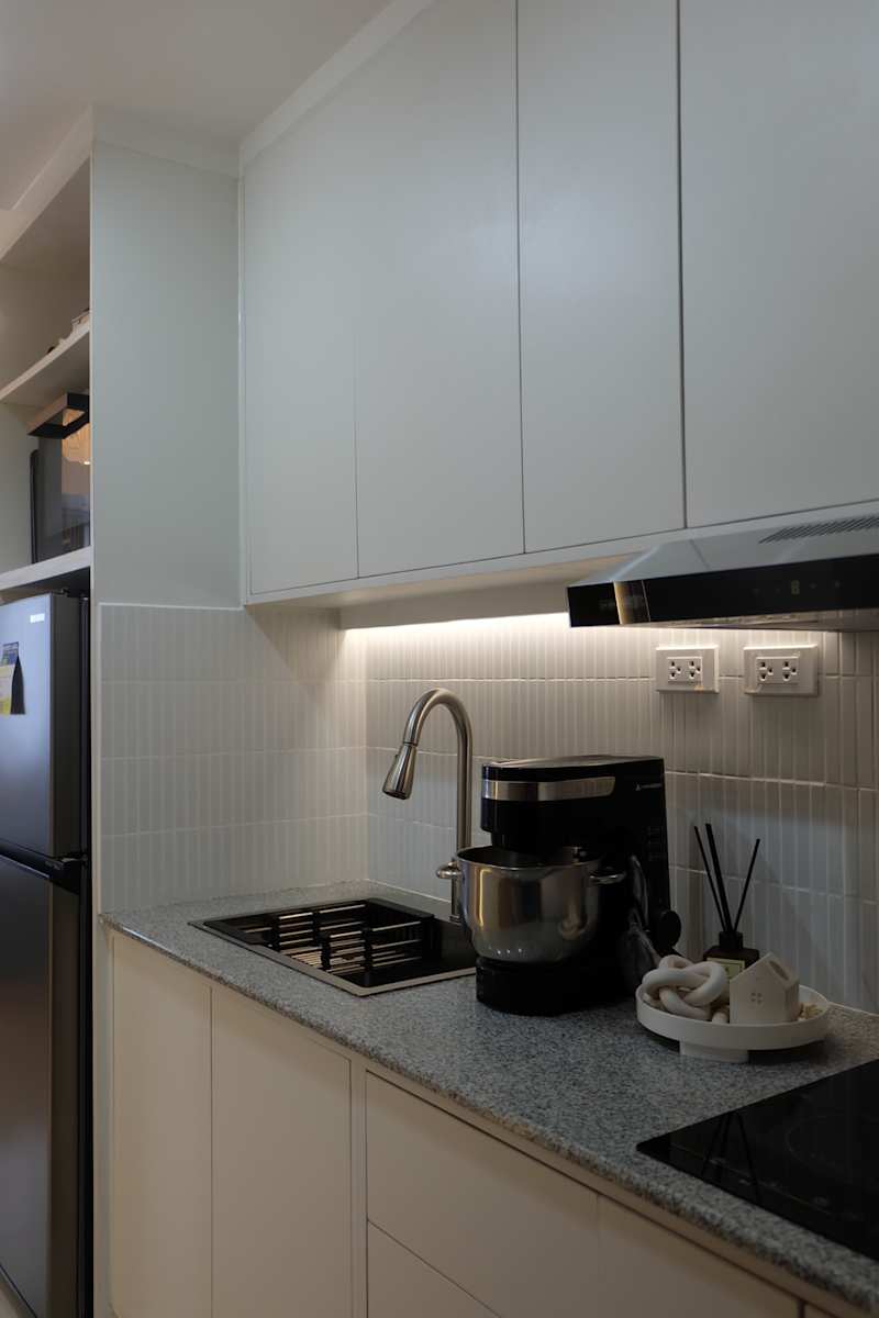 Modern kitchen with white cupboards, granite worktop, coffee machine and a sink made of stainless steel.