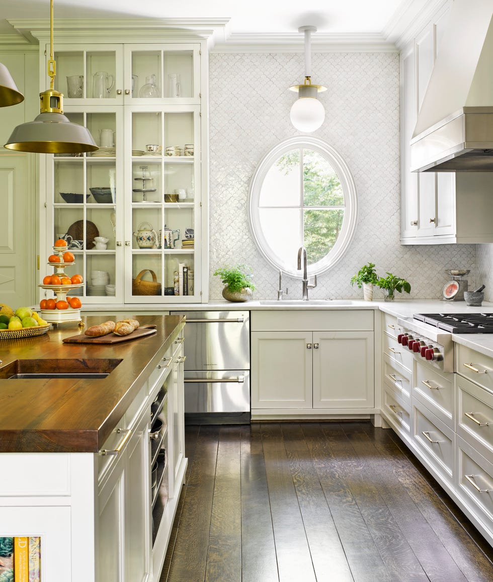 A white kitchen with an oval window and a shiny backplash tile