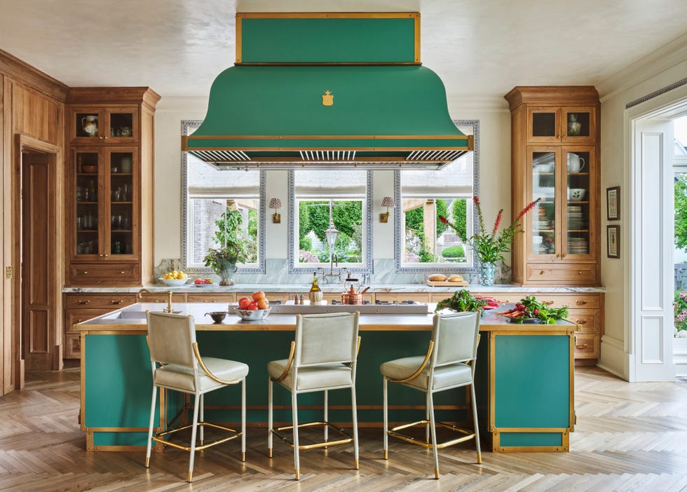 A green kitchen with a large island and a ceiling ventilation hood