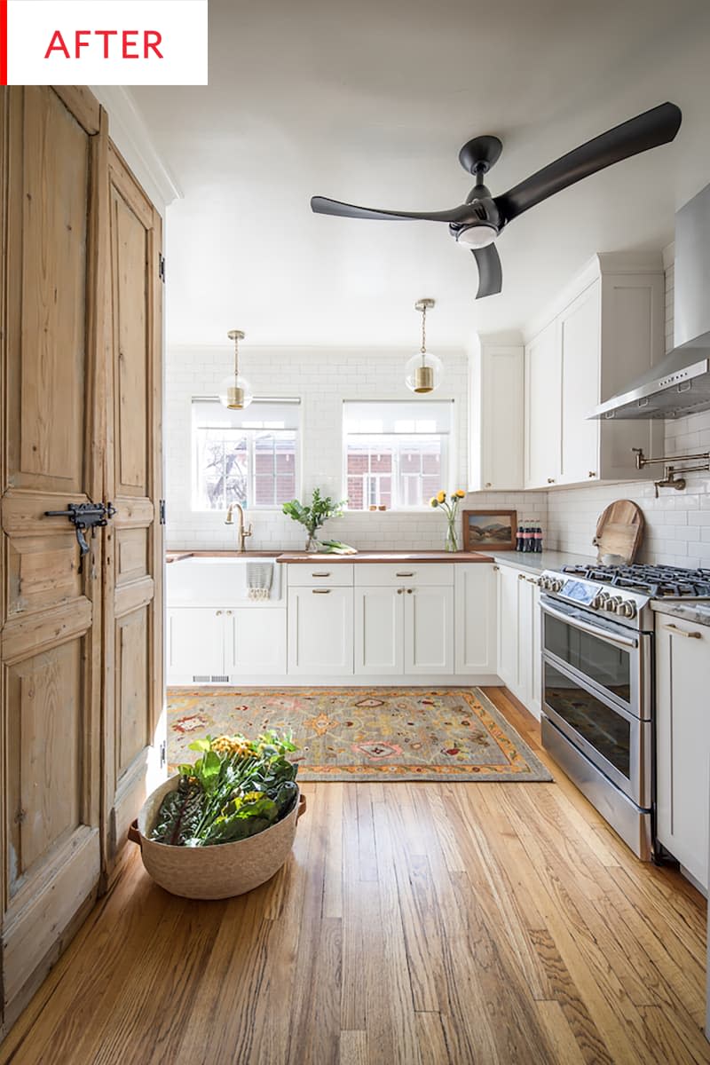 Bright kitchen with white cupboards, wooden panels, a colorful carpet, ceiling fan and a gem with green on the floor.