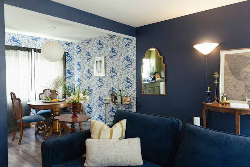 Cozy living area with a dark blue wall, a round wooden dining table and decorative plants.