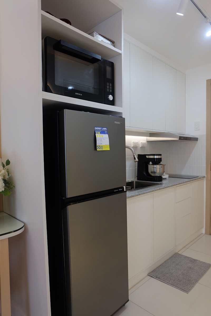 Modern kitchen with a stainless steel refrigerator, a black microwave and a blender on a granite worktop.