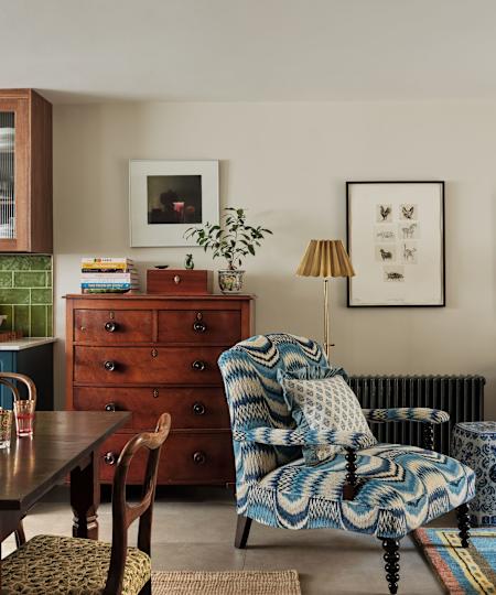 Vintage living room with wooden chest of drawers, padded armchairs and colorful carpet