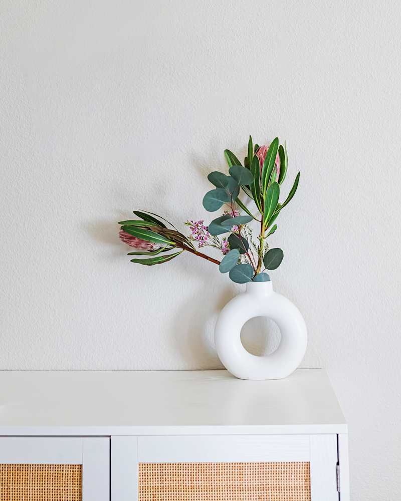 Minimalist residential culture. Sandstein-Donut-Form vase on the chest of drawers over the light gray wall