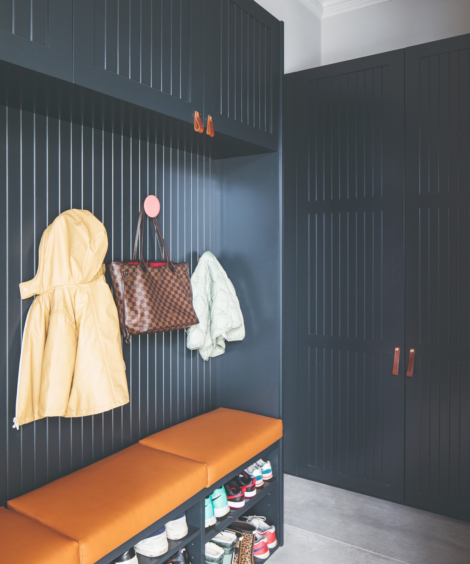 A hallway with a dark blue wardrobe and a suitable storage unit with an integrated shoe bench