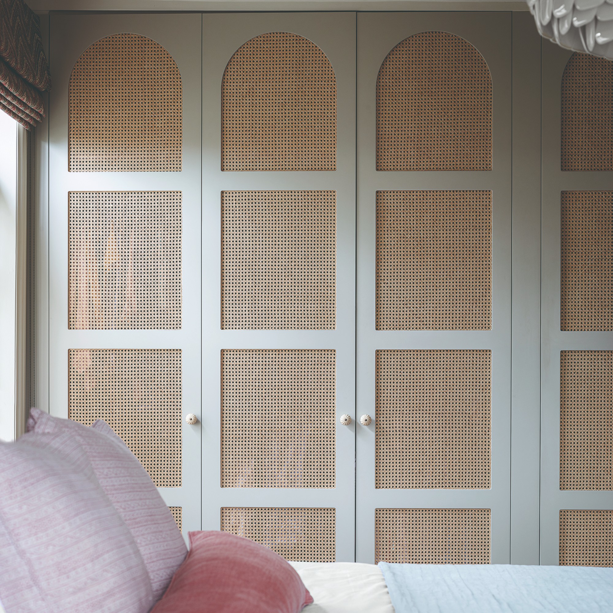 A bedroom with built -in wardrobes with curved cutouts filled with sugar cane network