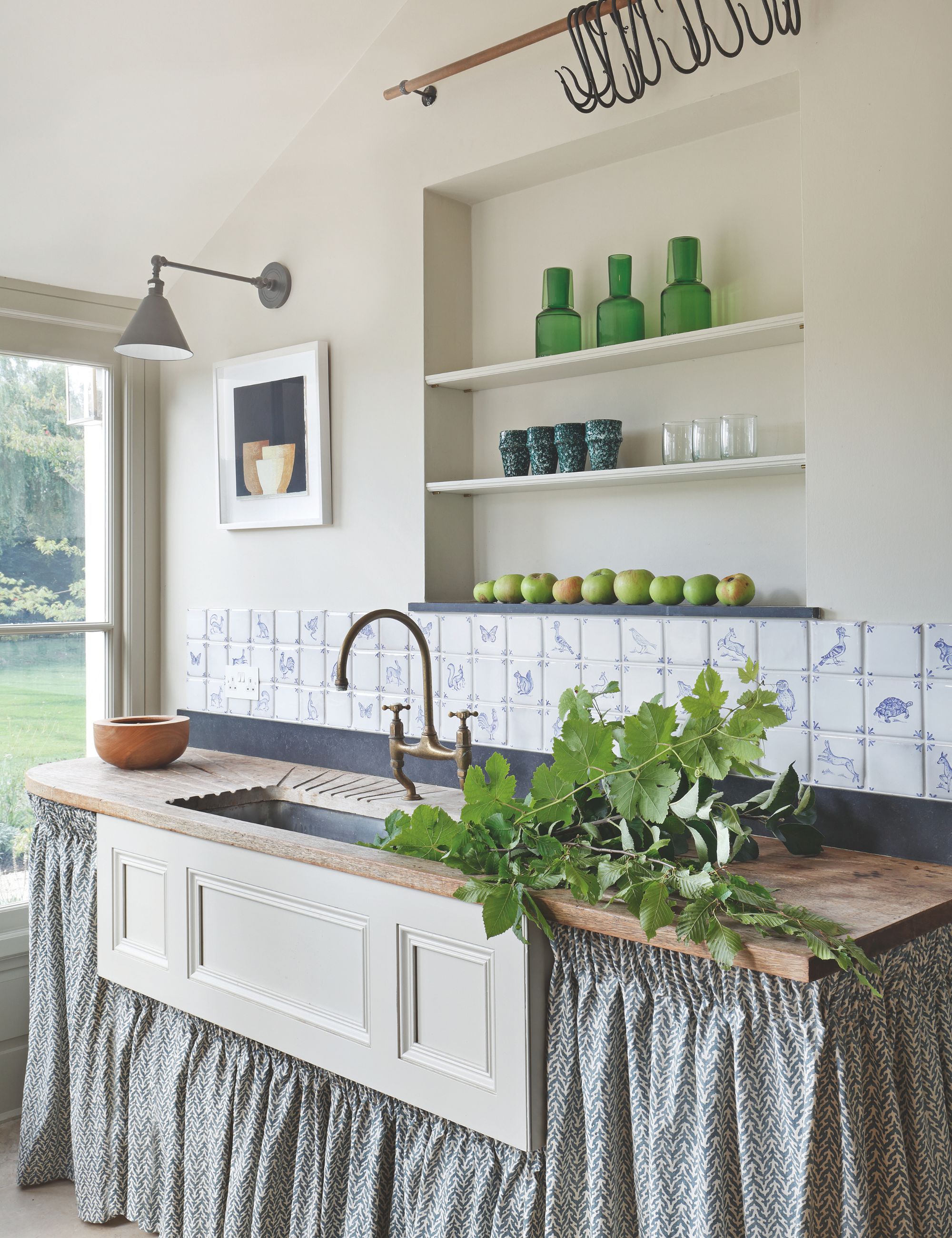 Cabinets, dolphin tiles and shelves with glasses and apples