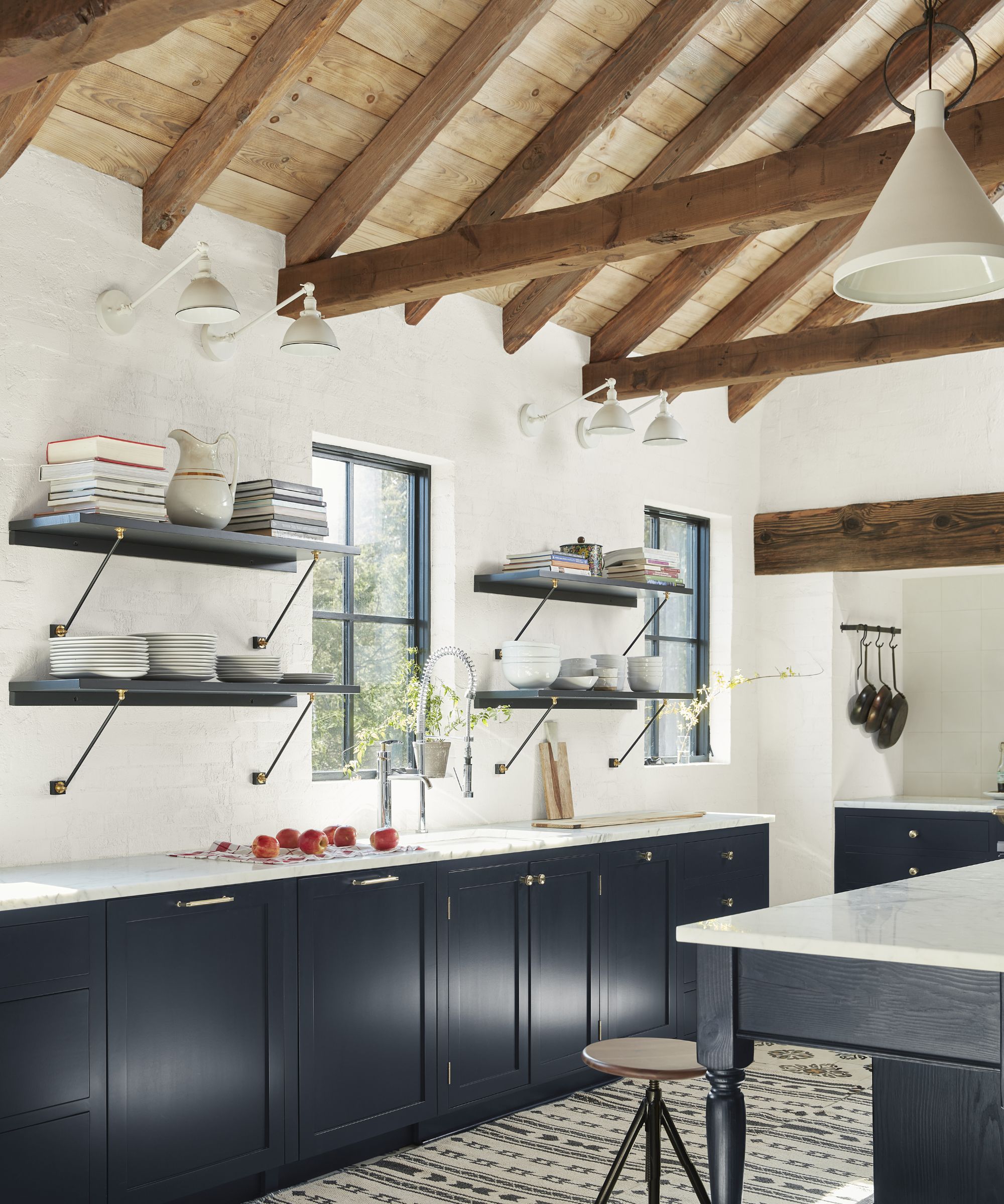A three -color kitchen with dark blue cupboards, white walls and a wooden ceiling