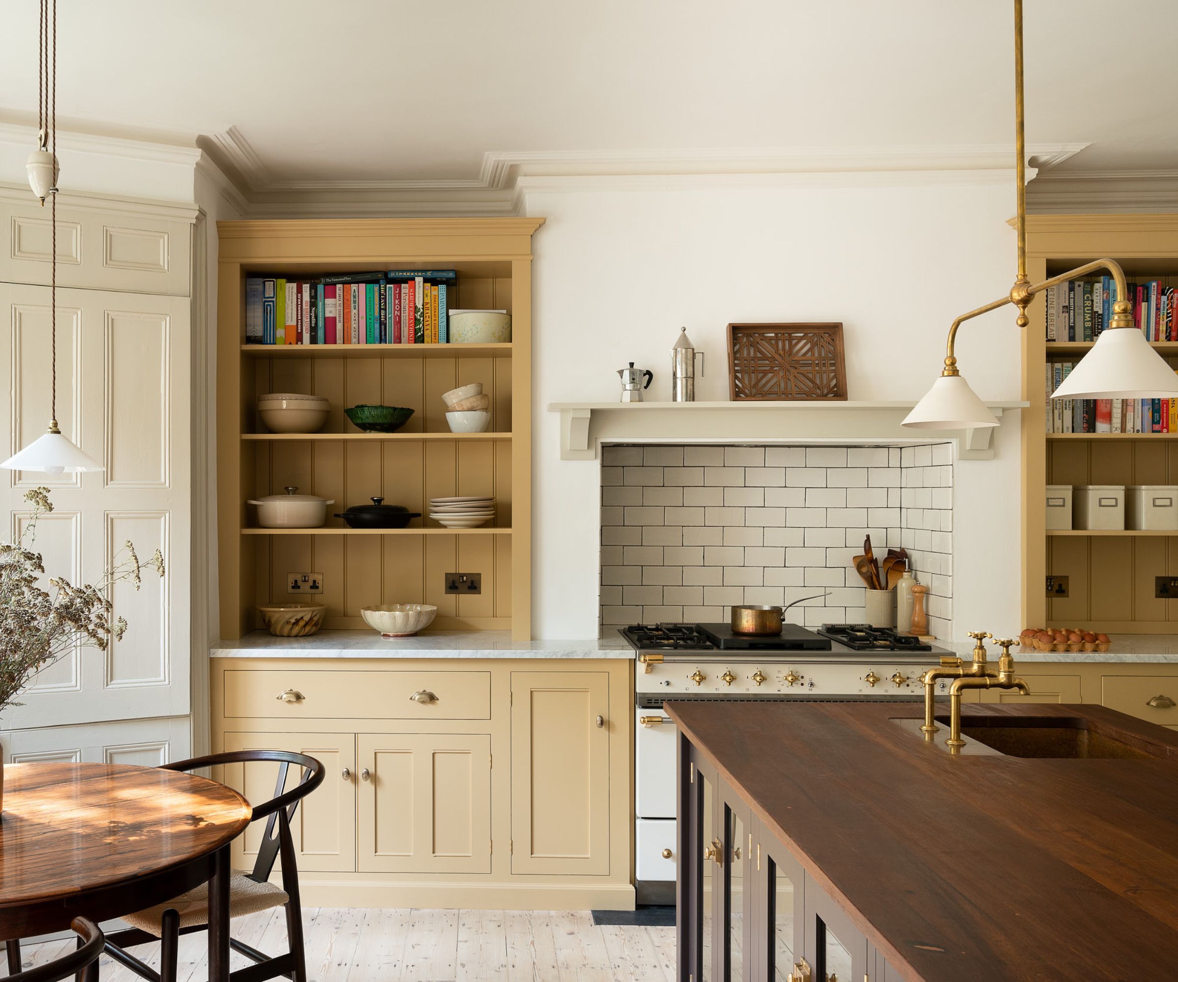 White and butter yellow kitchen with a traditional cooking cooker with white and gold range of butter yellow shelves