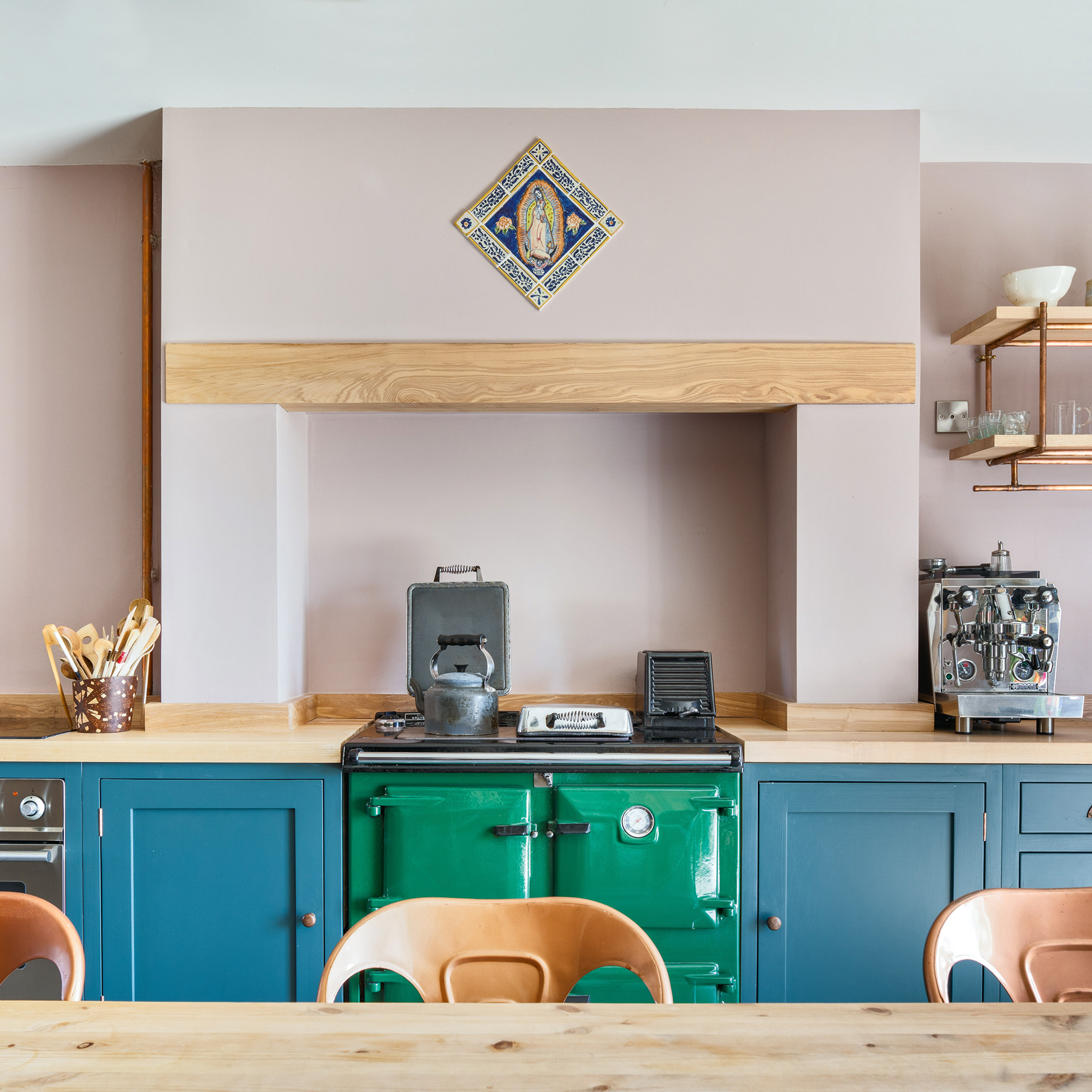 Pink walls in the kitchen with ash worktops and green reach with blue -painted cupboards in a country kitchen