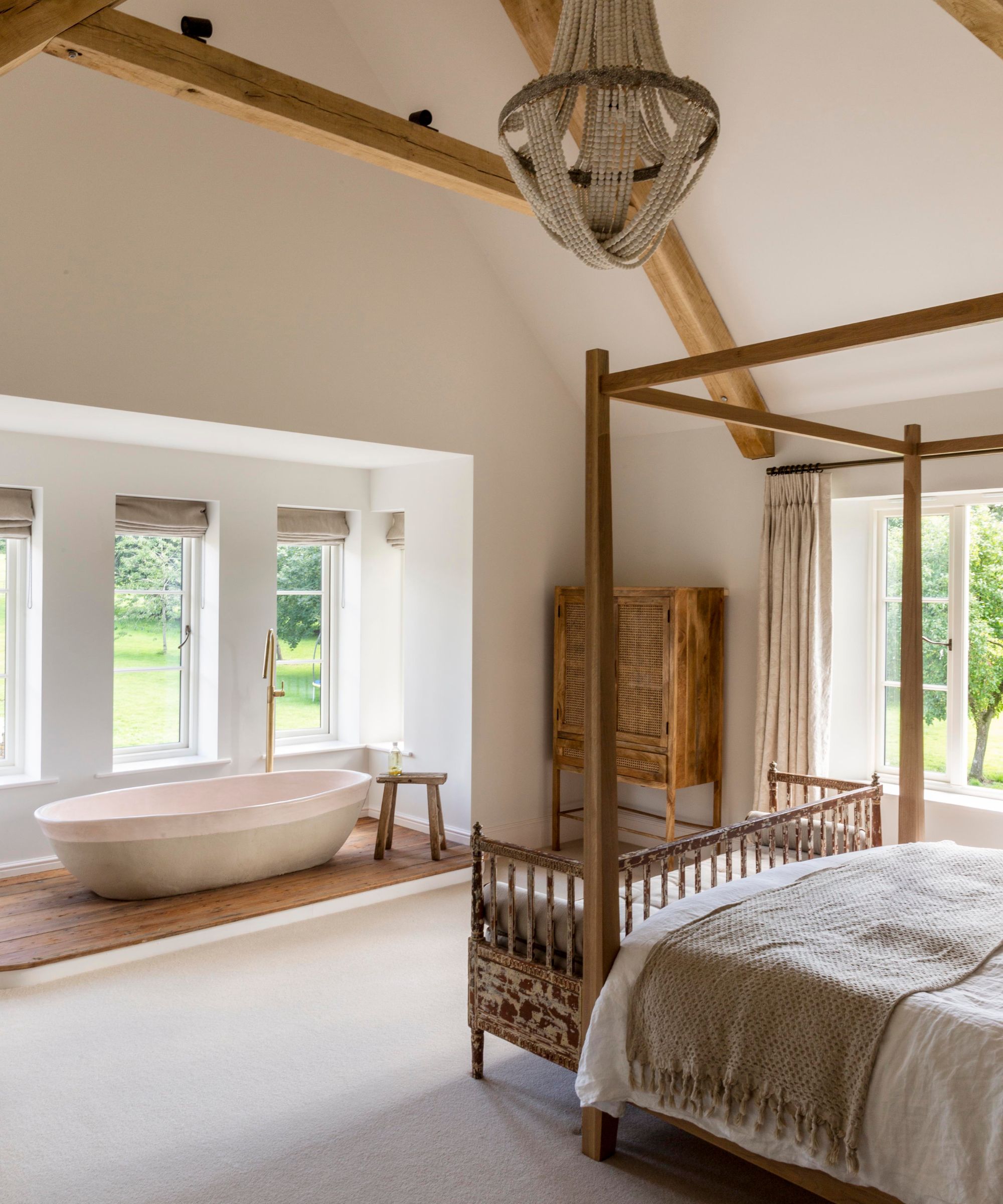 A large bedroom with a four -poster bed, curved blankets and a bathtub that was installed by the window