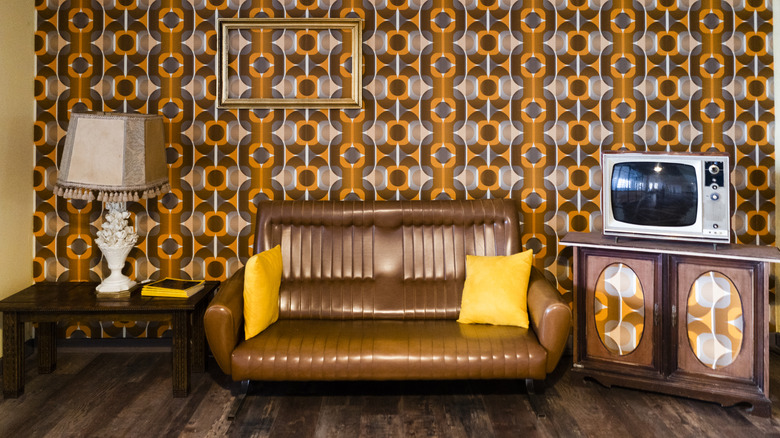 Retro living room with orange and brown wallpaper, wooden furniture and brown couch