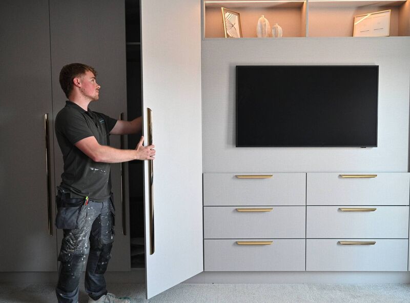 Adam O'Sullivan from AOS Carpentry & Tischlerei checks the doors of the textile gray robes in the main bedroom.