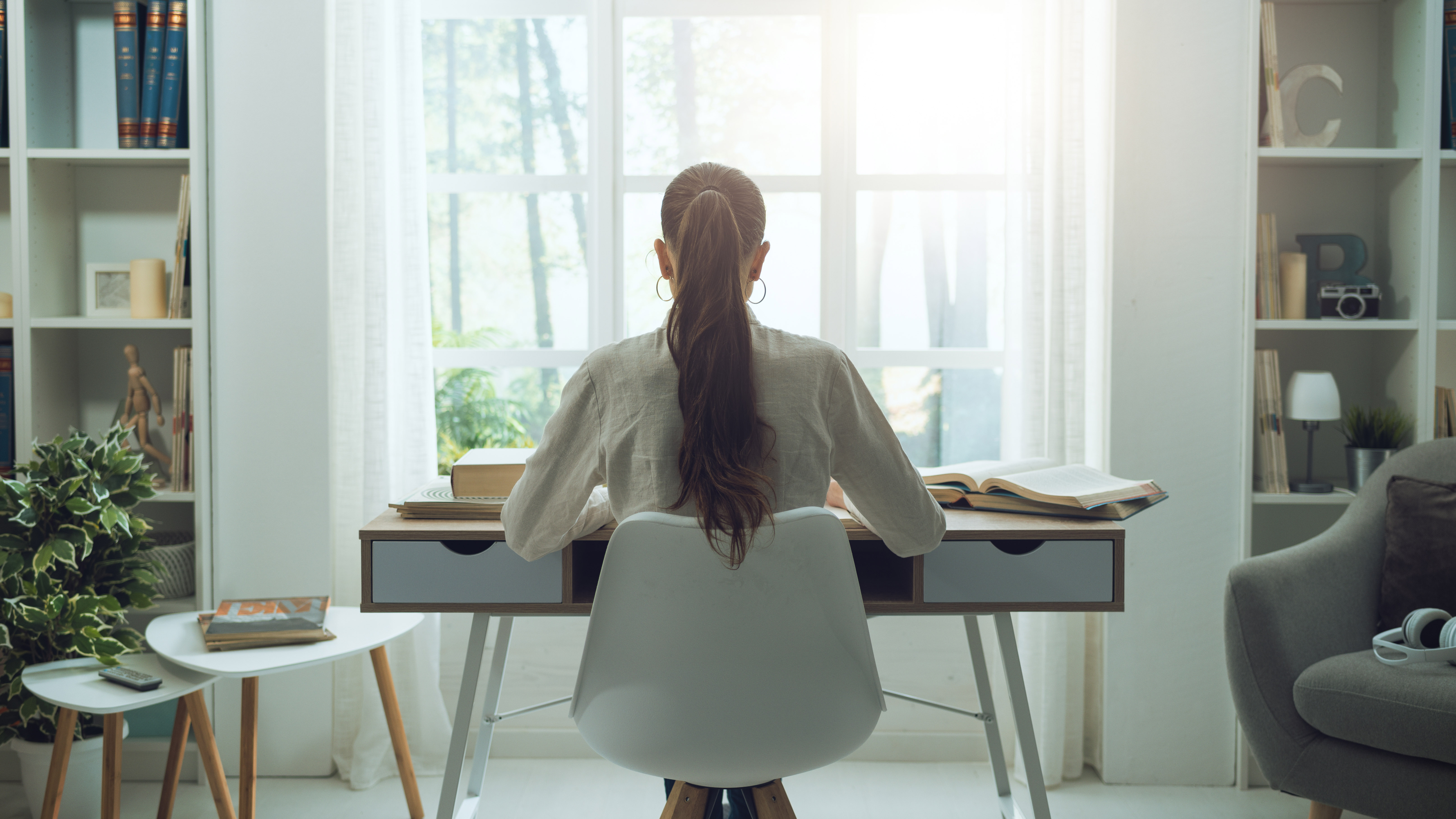 A woman sitting at a desk in front of a large window