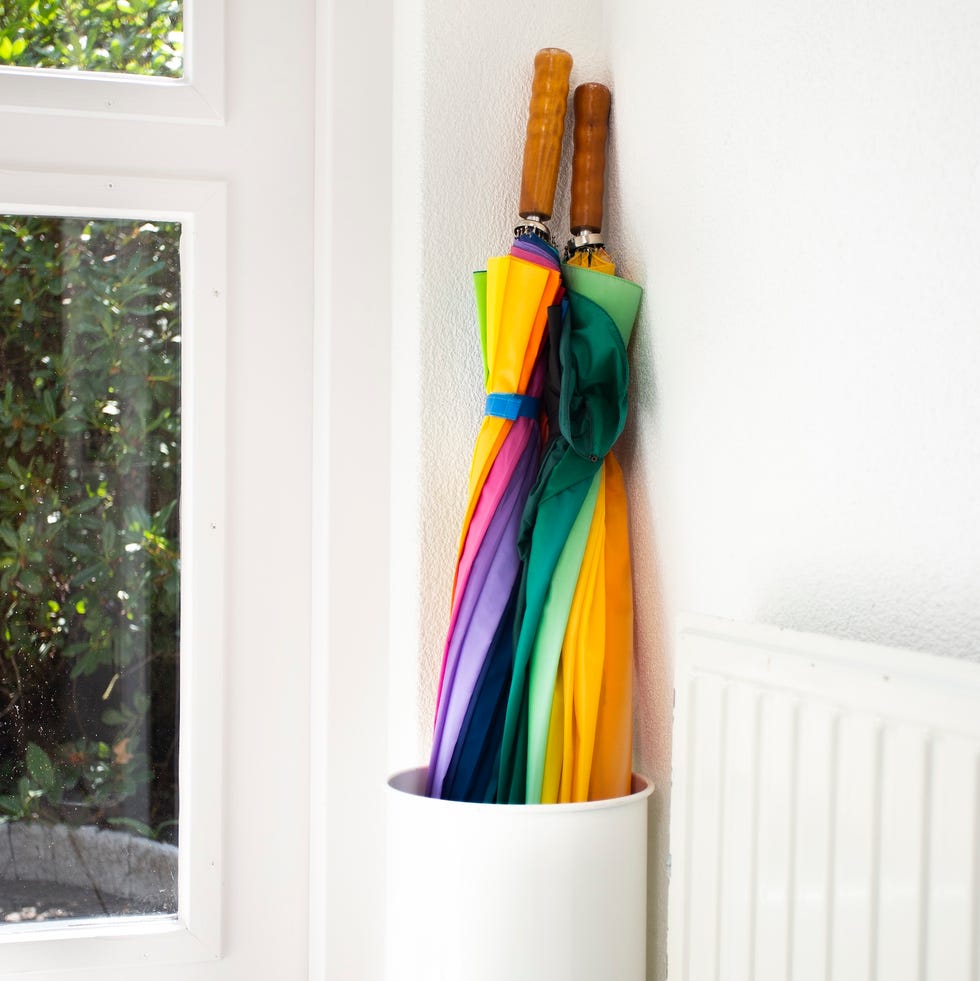 Use umbrella in the rainbow holder in the white hallway, modern design in the bright house next to the door colorful close -up