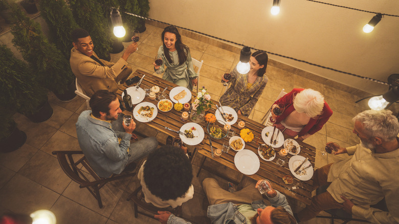 String lights hang outdoors over a dinner