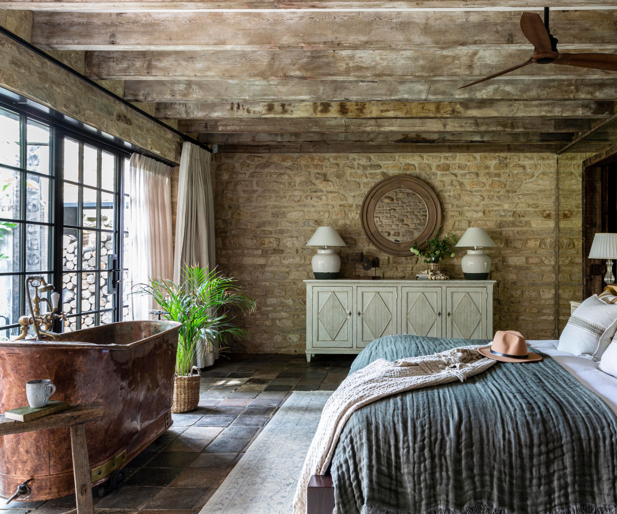 A bedroom in the country with exposed brick walls and a free -standing copper pool
