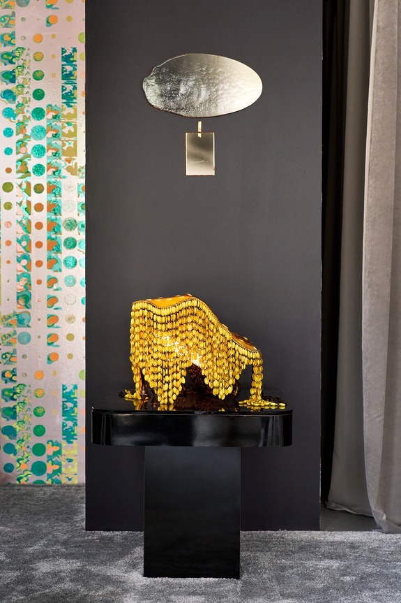 Decorative chair with yellow pearls on a black base in front of a dark wall background with an abstract patterned decor.