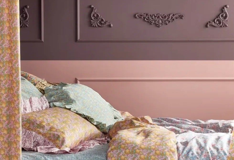 Flower bed linen in a bedroom in a vintage style with mauva walls and decorative molded parts.