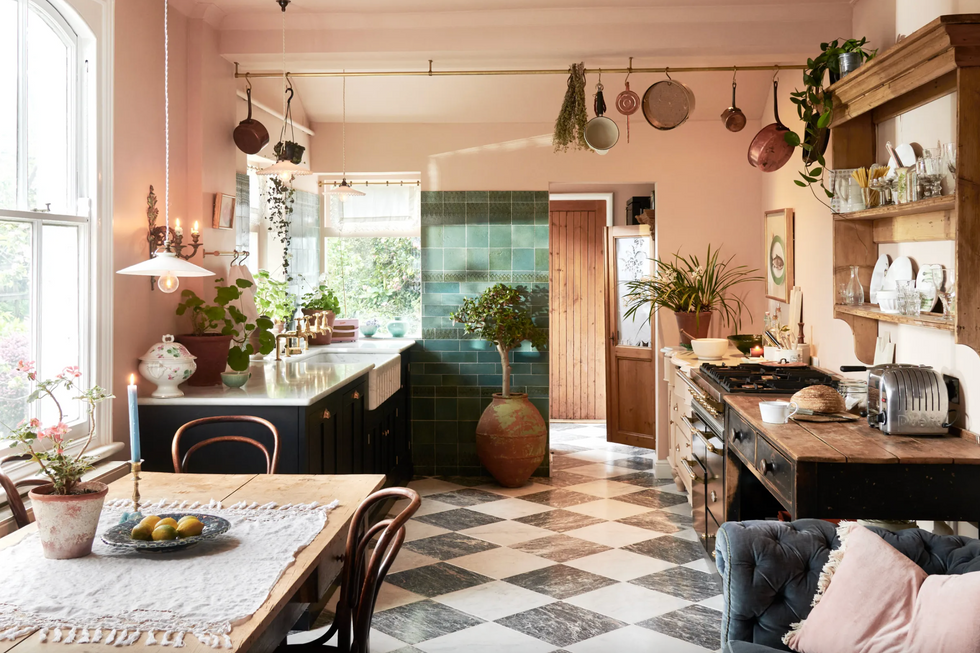 Rustic cuisine with green tiles, wooden furniture, plants and hanging pots.