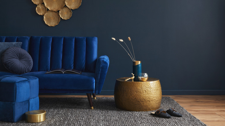 A stylish blue velvet sofa mixed with golden decorative pieces