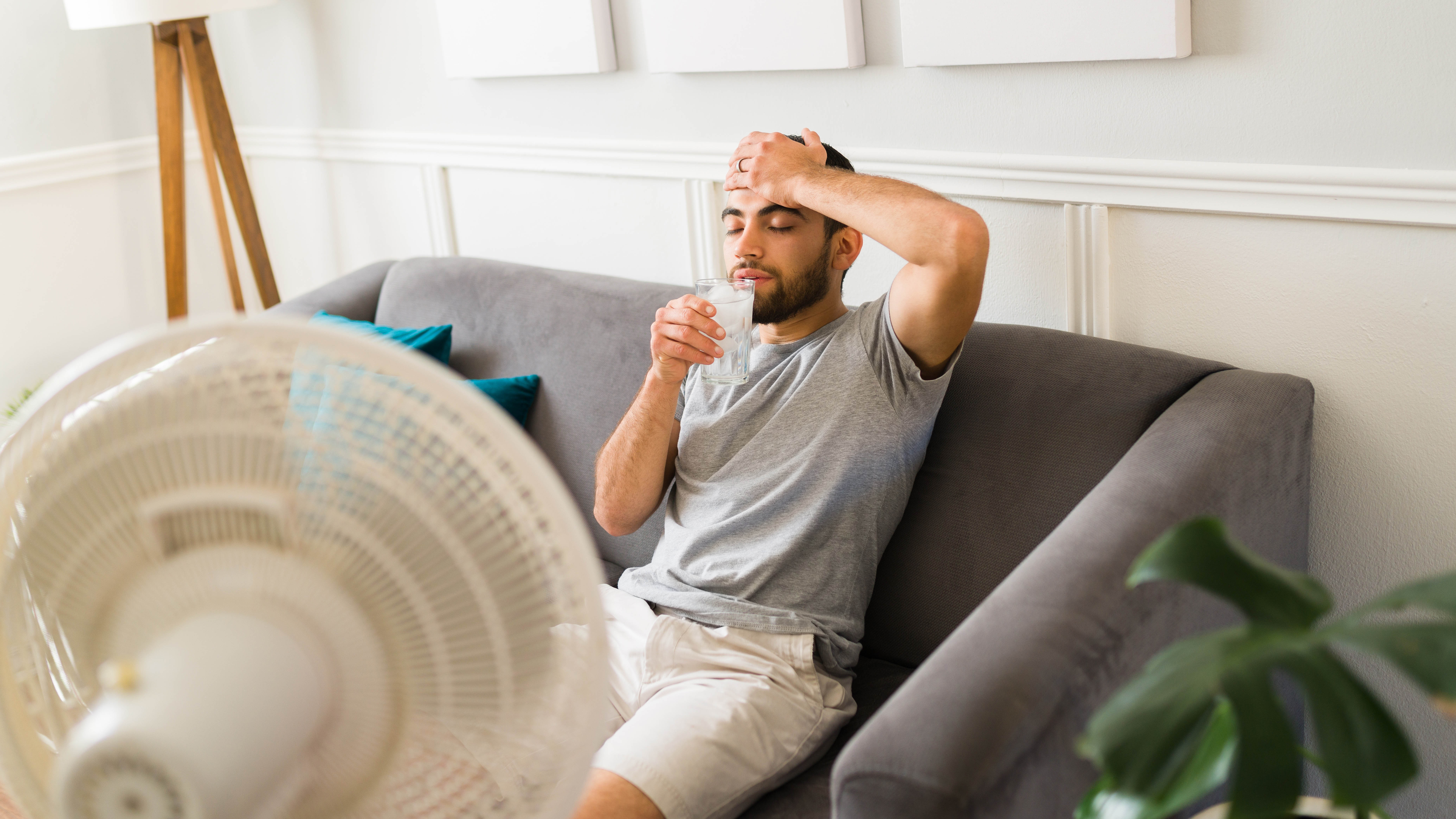 Schwitzer man drinks water in front of a fan