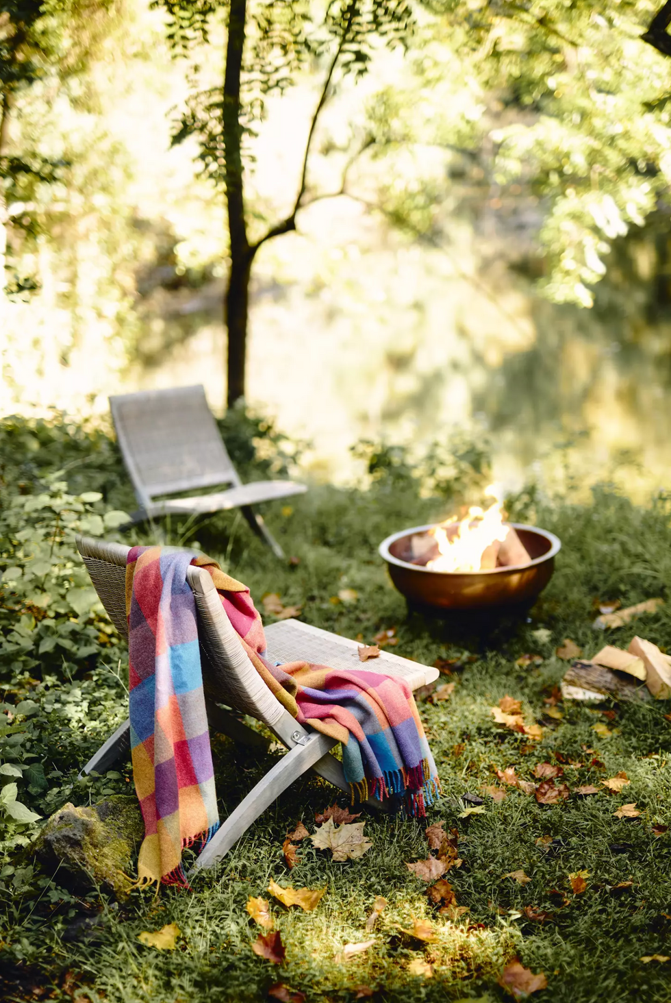 Chairs with a colorful ceiling through a fireplace in a lush, leafy garden environment.