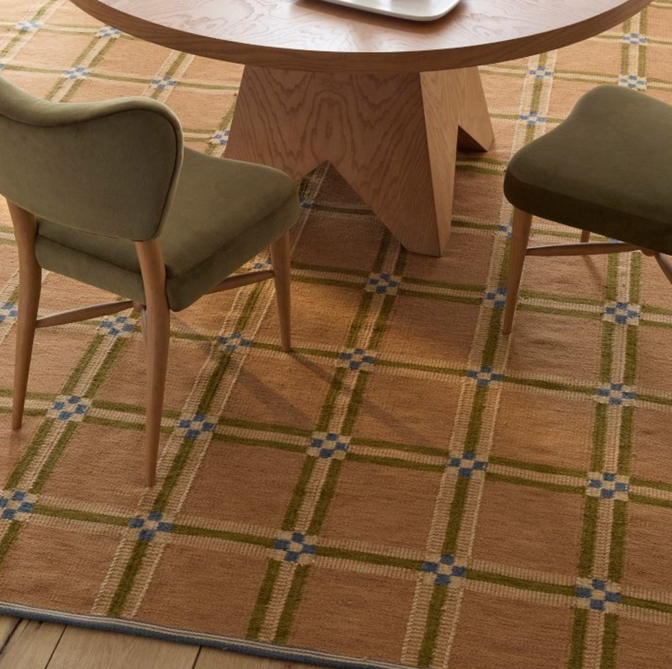 Round wooden table, green chairs on a checkered carpet with blue accents.