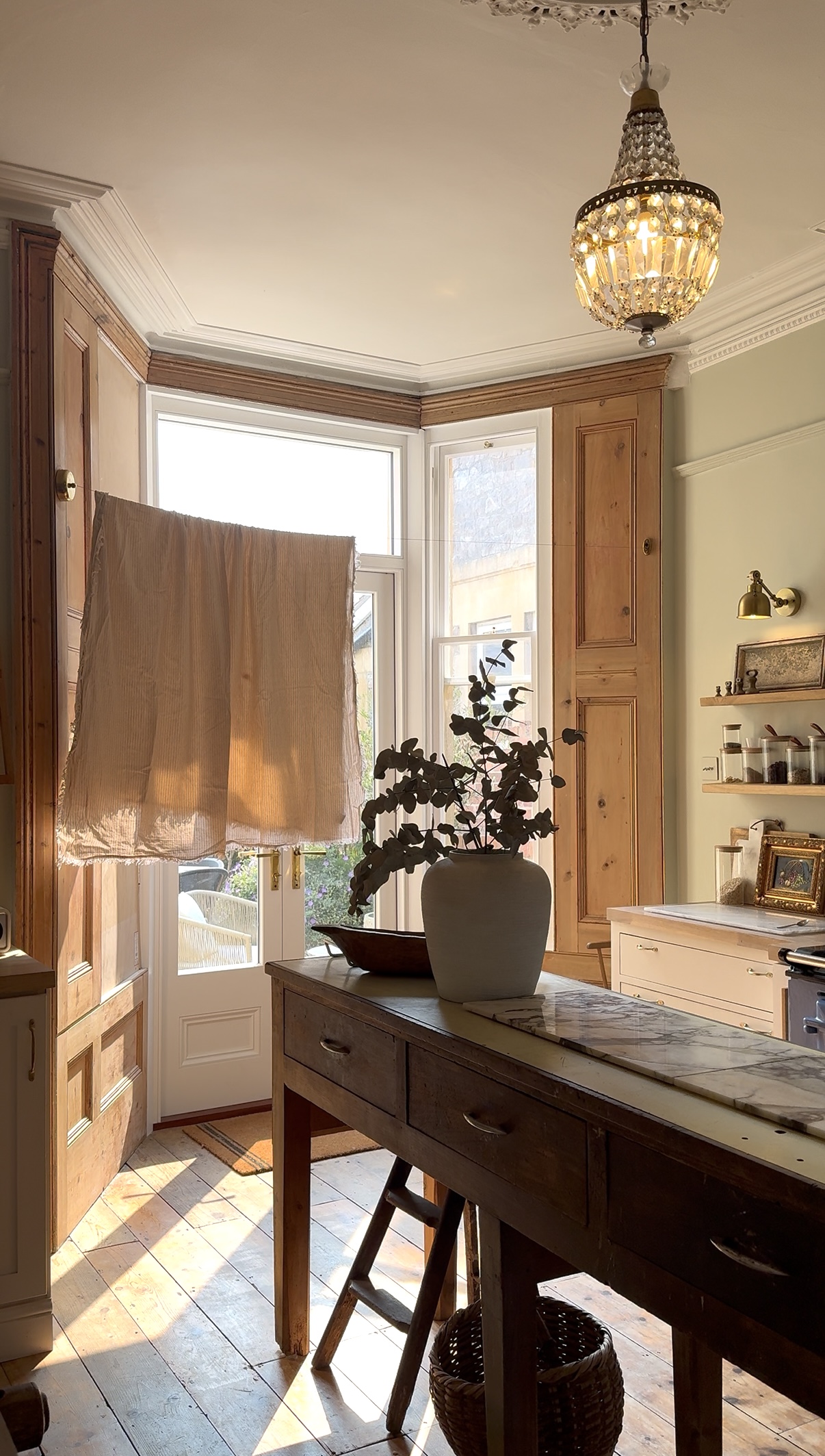 Image of rustic cuisine with a large bay window in which there is a retractable clothesline. There is a dark wooden kitchen island.