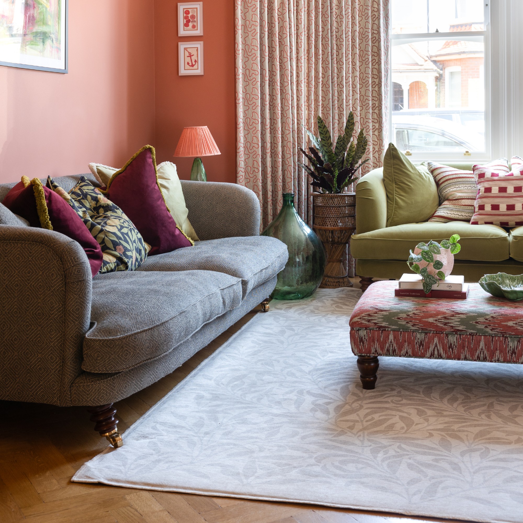 A terracotta orange living room with a gray and green sofa, which is decorated with multi-colored screecher