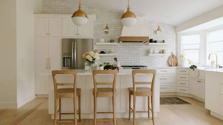 All-white cuisine with wooden chairs, brass hardware, back splash and wooden accent tiles