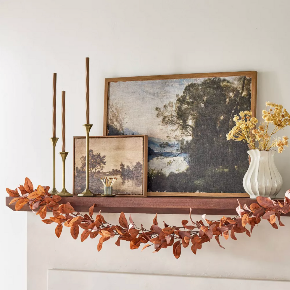 Coat with landscape paintings, candlesticks, vase and autumn leaf garland.