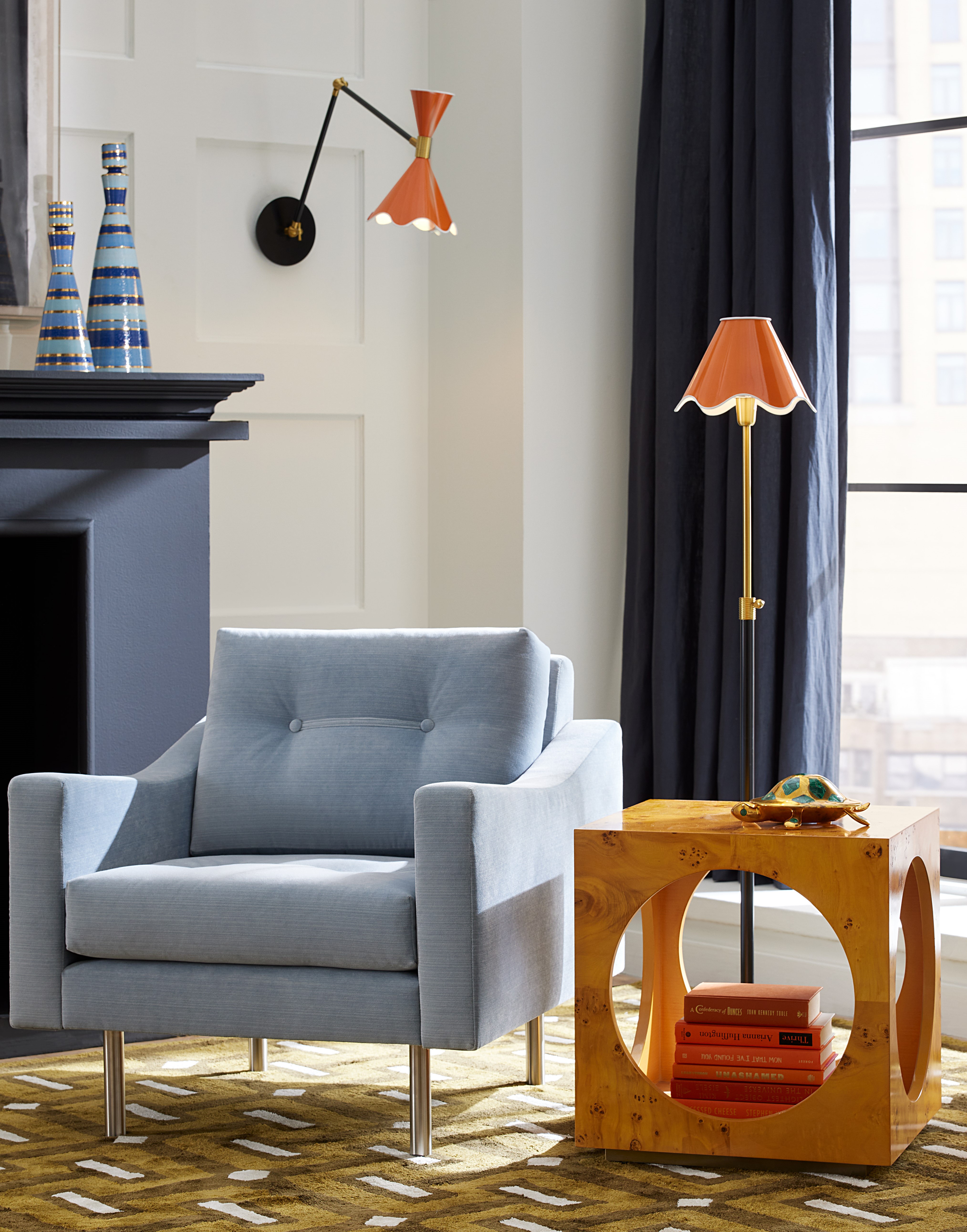 A fabric lamp with Jonathan Adler in an inspired living room from the middle of the century with a geometric green carpet and blue accent chair