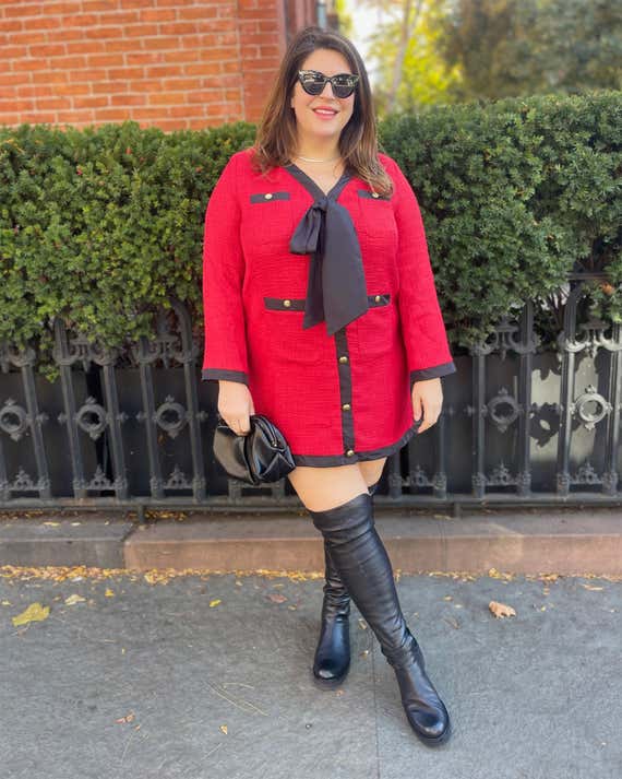 Katie Sturino wears a red outfit with high black boots in an outdoor environment.