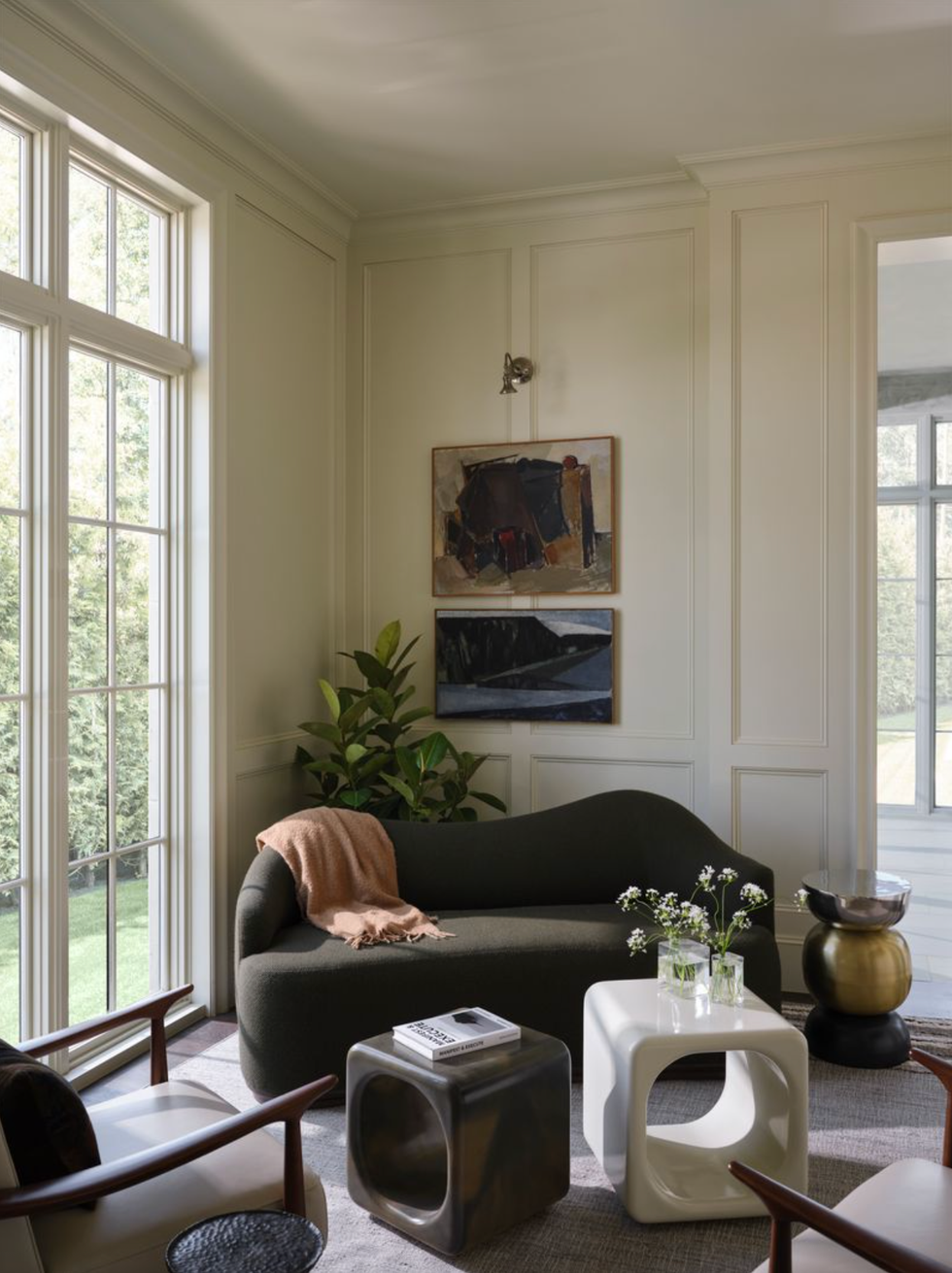 Cozy living room with dark sofa, abstract art and large windows.