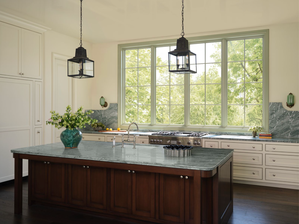 Spacious kitchen with large windows, island, green worktop and trailer lights.