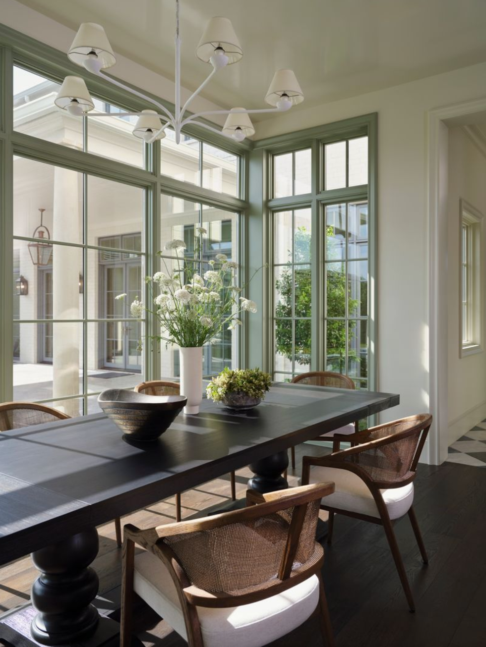 Sunshine room with dark table, chairs and large windows.