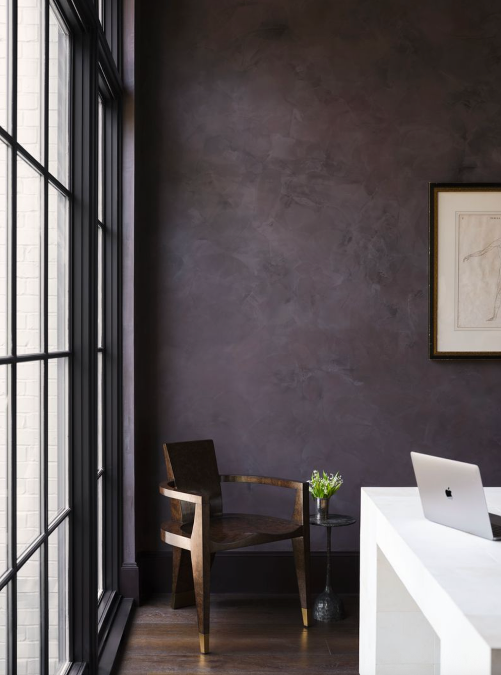 Minimalistic space with chair, table, laptop and large windows. Dark structured wall.