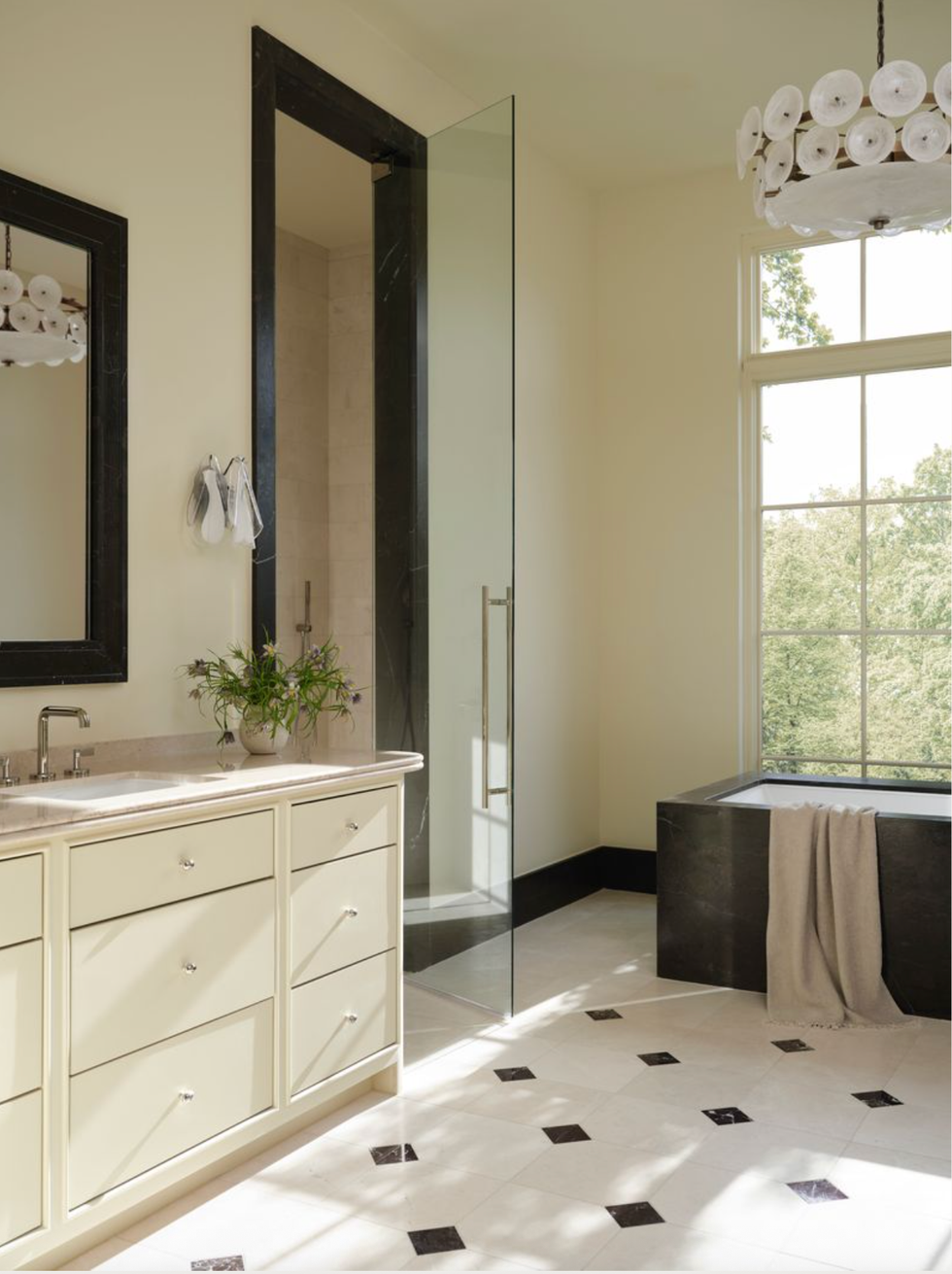 Modern bathroom with glass shower, tub, washbasin and large window with garden view.