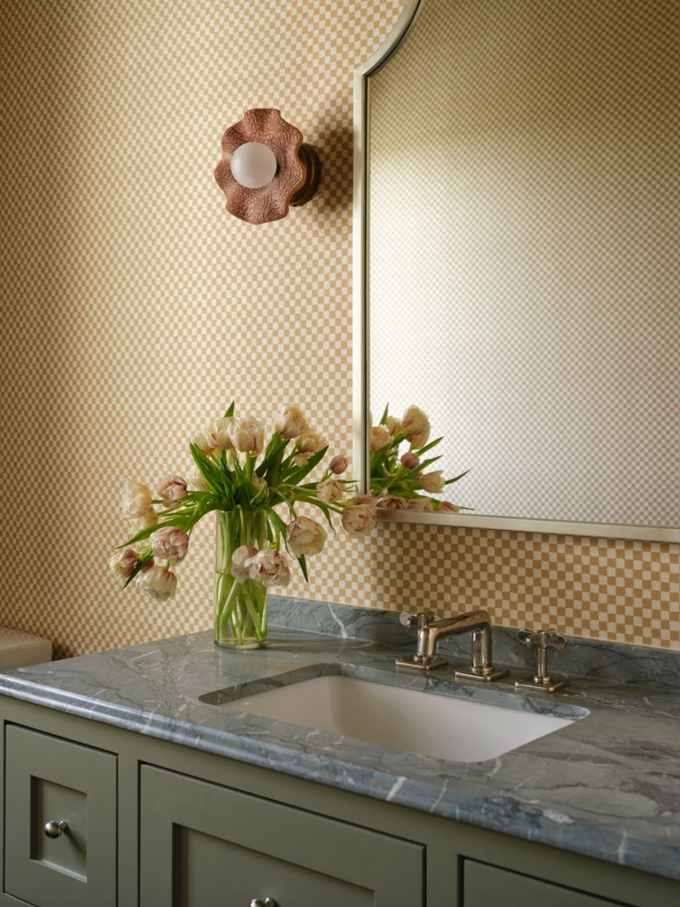 Elegant bathroom with tulip, green washbasin, marble slab, mirror and wall lights.