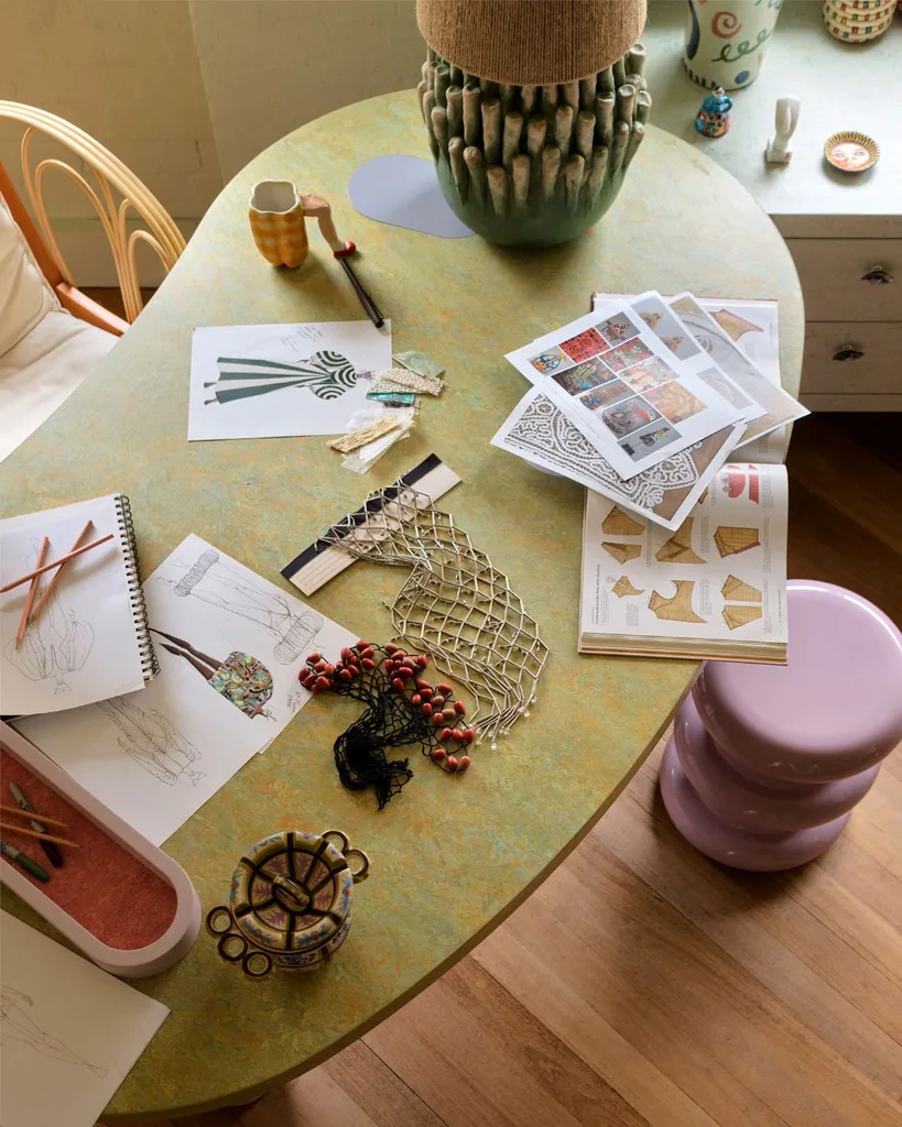 Overhead recording of the green, curved desk in Alemis Sydney Offices, covered with fashionable illustrations of future collections. 