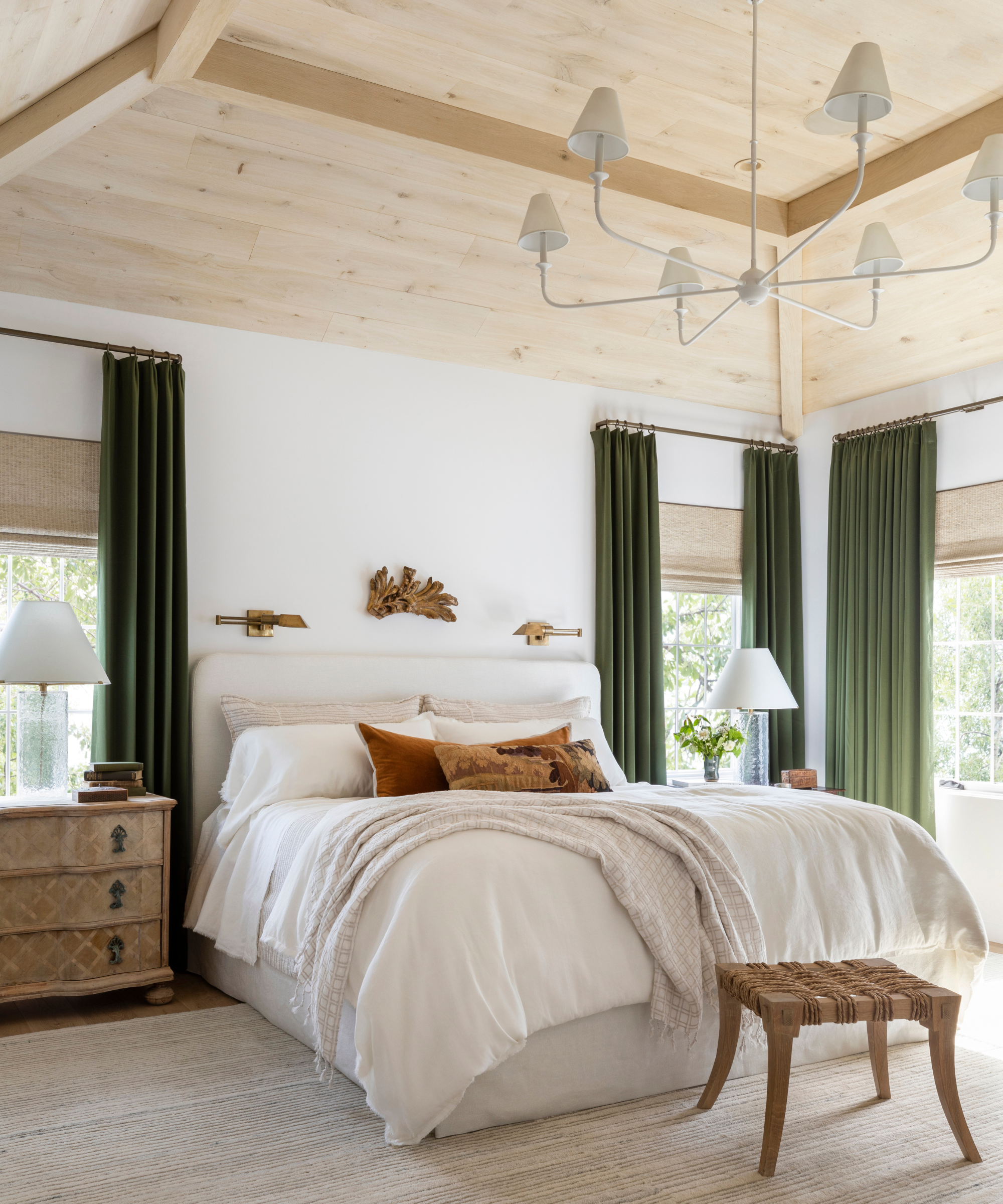 Quiet bedroom with white bed linen, olive green curtains, light wooden beams, white walls and soft neutral decor